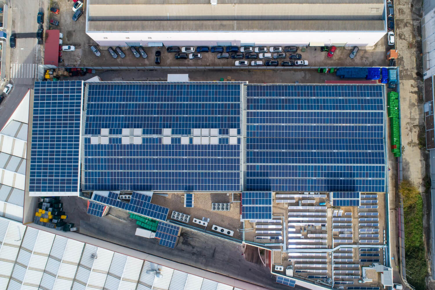 Vista aerea di un impianto fotovoltaico industriale installato sul tetto di un capannone, con pannelli solari disposti su ampia superficie per l’autoproduzione di energia.